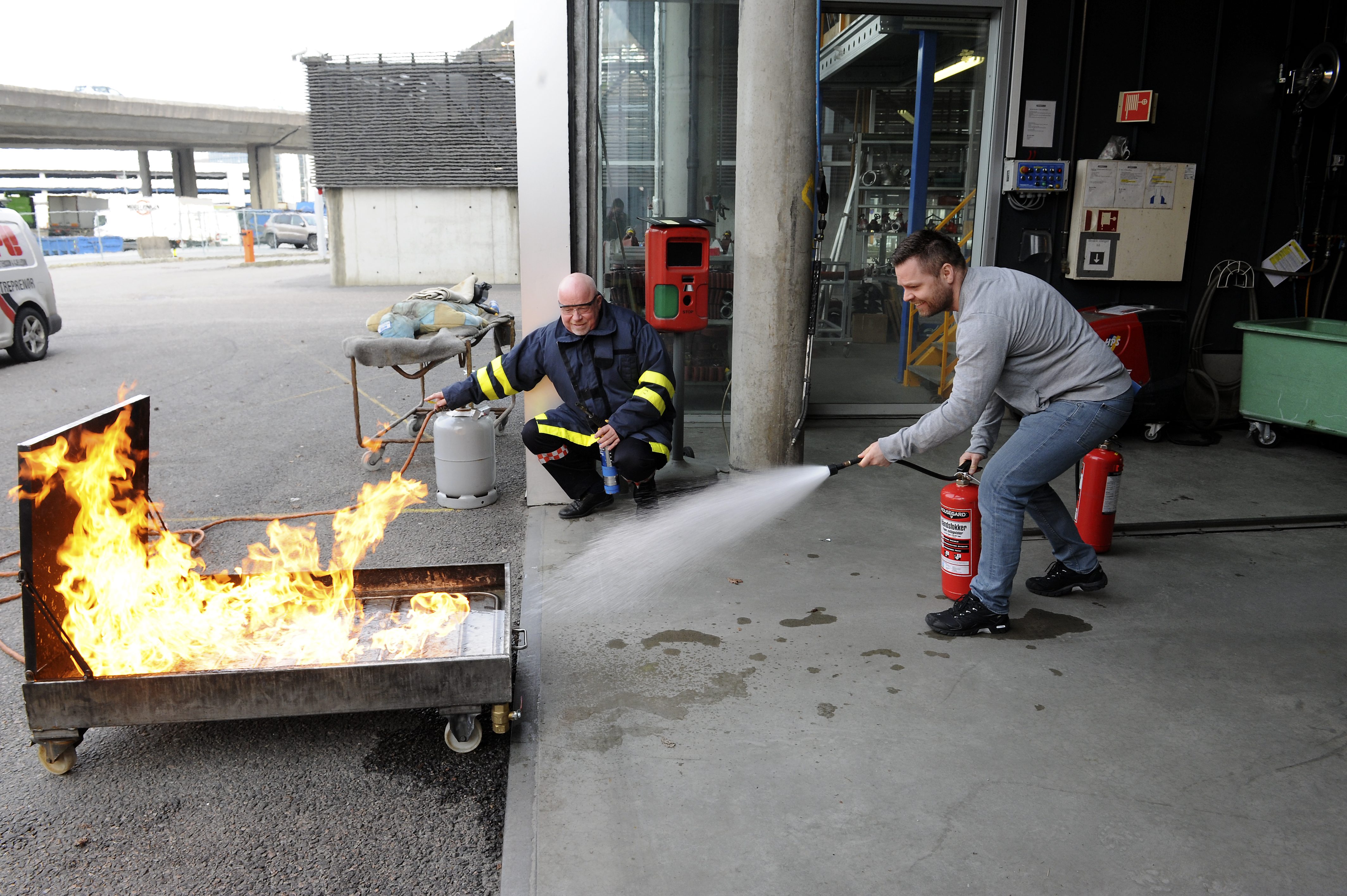 Person slukker brann i gasskar med skumapparat. Fotograf: Marius Solberg Anfinsen. Foto.